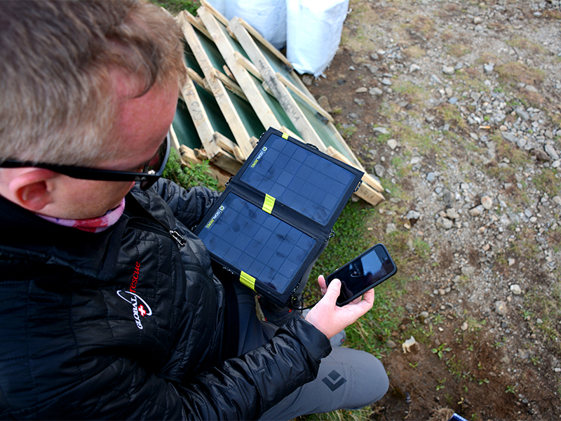 Especialista en operaciones de Global Rescue utilizando un teléfono con panel solar