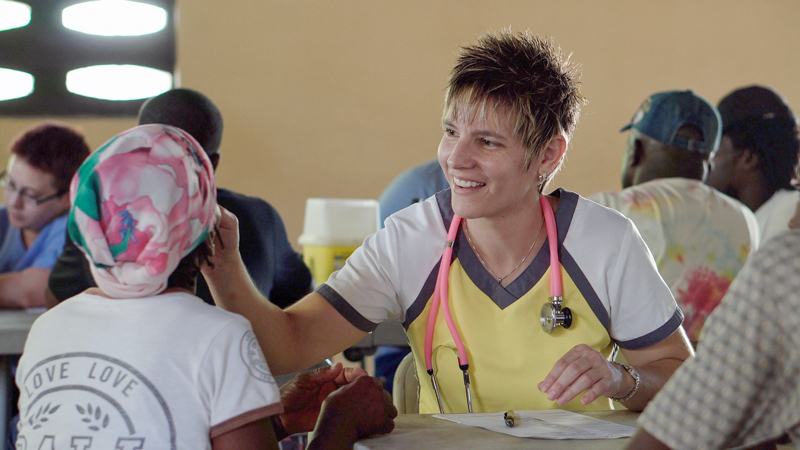 médica misionera atendiendo a un paciente en una habitación con otros cooperantes